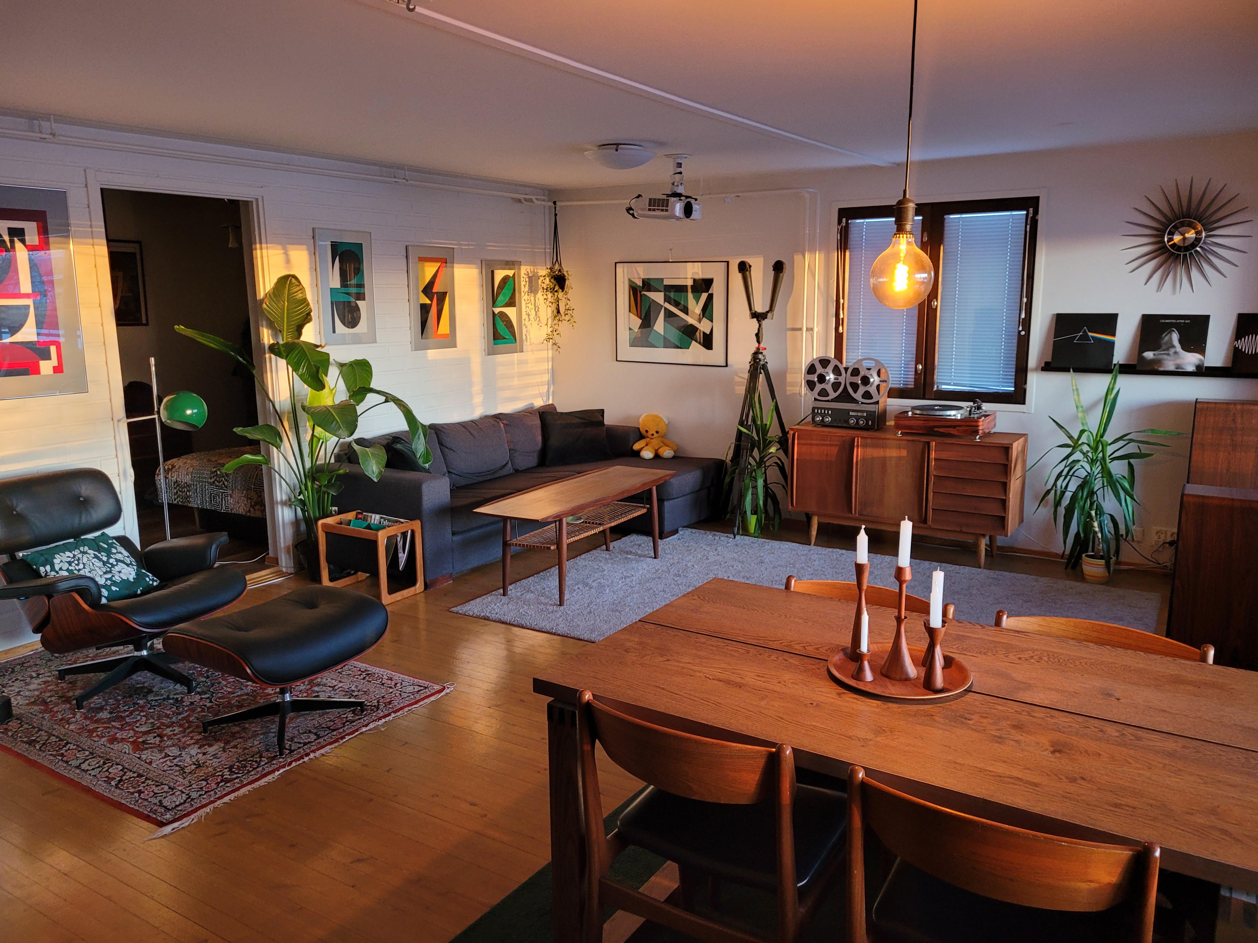 This living space is a perfect blend of mid-century modern design and natural warmth. The wood accents throughout the space create a welcoming atmosphere, while the carefully curated furniture pieces and decor add character and personality. The use of plants, including a stunning Bird of Paradise, brings life and color to the room. The attention to detail is evident in the choice of serigraphies and the placement of records. The overall effect is a cozy and inviting space that is both stylish and comfortable. /2023_03_12_11pgmof/ljquap937dna1.jpg